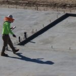 Engineer inspecting concrete slab at construction site in daylight.