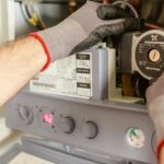Close-up of hands adjusting a boiler system with precise instrumentation, showing maintenance work.