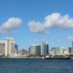 View of San Diego skyline with tall buildings and a ship on a bright day.